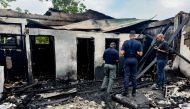 Investigators and government employees inspect the school dormitory where a fire killed at least 19 people in Mahdia, Guyana on May 22, 2023. (Photo by Keno George / AFP)
