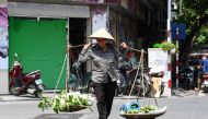 A street vendor carries mangoes in Hanoi on June 1, 2023. (Photo by Nhac Nguyen / AFP) 