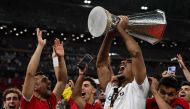 Sevilla's French defender Loic Bade (R) carries the trophy as he celebrates with the fans after winning the UEFA Europa League final football match between Sevilla FC and AS Roma at the Puskas Arena in Budapest on May 31, 2023. (Photo by VLADIMIR SIMICEK / AFP)