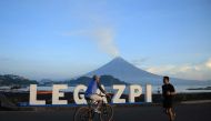 Residents exercise as Mayon volcano spews white smoke in Legaspi City, Albay province on June 7, 2023. (Photo by Charism SAYAT / AFP)
