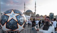 A man takes a picture of a giant replica of the Champions League soccer ball at Taksim Square on June 9, 2023 on the eve of the UEFA Champions League final between Inter Milan and Manchester City. (Photo by Umit Turhan Coskun / AFP)