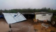 A man inspects tin roofing damaged by strong winds at Moti-Bhadai village some 20 Km from the coastal town of Mandvi in Kutch district on June 16, 2023, after Cyclone Biparjoy made landfall. Photo by AFP