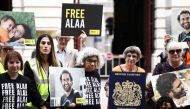 Protesters including Laila Soueif (centre), mother of jailed British-Egyptian activist Alaa Abdel Fattah, hold his pictures along with placards of British passport covers and signs reading 