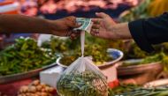 A customer buys vegetables from a stall at a market in Karachi on July 3, 2023. (Photo by Asif HASSAN / AFP)

