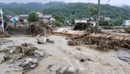 A man (L) looks at debris from flooding in the road in Tanushimarumachi in the city of Kurume, Fukuoka prefecture, on July 10, 2023, after heavy rains hit wide areas of Kyushu island. Photo by JIJI Press / AFP
