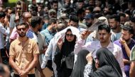 Protesters shade themselves as they march at a demonstration against water scarcity and power outages in Baghdad on July 18, 2023 during a heat wave. (Photo by Murtaja LATEEF / AFP)
