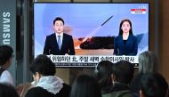 People watch a television screen showing a news broadcast with file footage of a North Korean missile test, at a railway station in Seoul on July 22, 2023. (Photo by Jung Yeon-je / AFP)
