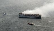 This handout photograph taken on July 29, 2023 and released on July 30, 2023 by the Dutch coastguards, shows smoke rising from the Panamanian-registered car carrier ship Fremantle Highway, after a fire broke out late on July 25, 2023, killing one crew member, and prompting a massive effort to extinguish the flames. Photo by Handout / Netherlands Coastguards / AFP