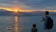 Tourists take photographs during sunset in the city of Nafplion, southern Greece, on July 31, 2023. Photo by Louisa GOULIAMAKI / AFP