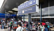 View of the entrance of the Orly 4 terminal with a sign (C) indicating the other Orly terminals and passangers waiting next to baggage carts stacked with luggage, after a technical incident at the Paris-Orly Airport, in Orly, south of Paris.