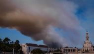 A column of smoke billows above the Sanctuary of Our Lady of Fatima, after a wildfire broke out in Fatima on August 5, 2023. Photo by CARLOS COSTA / AFP