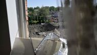 A view taken through a shattered window pane shows the crater of a missile that fell between residential buildings and a kindergarten in the city of Lviv, western Ukraine, on August 15, 2023, amid Russian invasion in Ukraine. Photo by Genya SAVILOV / AFP