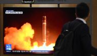 A man walks past a television screen showing a news broadcast with file footage of a North Korean missile test, at a railway station in Seoul on August 24, 2023. (Photo by Jung Yeon-je / AFP)