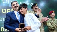 This handout photo taken and released by Pakistan's Press Information Department on August 24, 2023, shows Pakistani caretaker Prime Minister Anwaar-ul-Haq Kakar (left) greets a survivor of the cable car accident during a ceremony in honor of rescuers efforts in cable car accident at the Prime Minister office in Islamabad. (Photo by Pakistan PRESS INFORMATION DEPARTMENT / AFP)