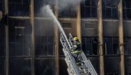 Graphic content / A firefighter extinguishes the fire at a building in Johannesburg on August 31, 2023. Photo by Michele Spatari / AFP