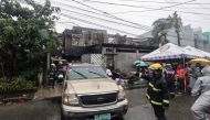 Firemen direct a vehicle after a fire at a house in Quezon City, suburban Manila on August 31, 2023. Photo by AFP