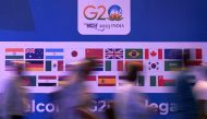 People walk past a banner with flags of countries participating in G20 summit at the International Media Center (IMC) at G20 venue on the eve of the two-day G20 summit in New Delhi on September 8, 2023. (Photo by Tauseef Mustafa / AFP)