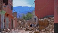 People walk past a destroyed house near Amizmiz in Morocco's worst-hit province of al-Haouz on September 11, 2023. (Photo by AFP)