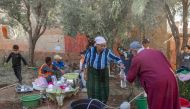 Displaced people work in a kitchen area at a makeshift encampment by the side of the road between Marrakech and Taroudant in the Atlas mountain range in the aftermath of a powerful earthquake on September 16, 2023. (Photo by Bulent Kilic / AFP)