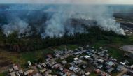 The smoke from a fire in a forest area approaches houses at the Cacau Pirera District in Iranduba, Amazonas state, Brazil on September 25, 2023. (Photo by Michael Dantas / AFP)
