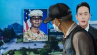 (Files) In this photo taken in Seoul on August 16, 2023, a man walks past a television showing a news broadcast featuring a photo of US soldier Travis King (C). (Photo by Anthony Wallace / AFP)
