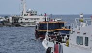 (Files) Chinese coast guard ships (L and R) corral a Philippine civilian boat chartered by the Philippine navy to deliver supplies to Philippine navy ship BRP Sierra Madre in the disputed South China Sea, on August 22, 2023. (Photo by Ted Aljibe / AFP)