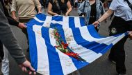 Demonstrators and students symbolically carry a blood-stained Greek flag with red flowers, during a march towards the US embassy in Athens on November 17, 2023, to commemorate the 50th anniversary of the 1973 students' uprising against a US-backed junta. (Photo by Theophile Bloudanis / AFP)
