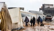 Palestinians walk under the rain at a camp for displaced people in Rafah, in the southern Gaza Strip where most civilians have taken refuge, on December 13, 2023. (Photo by Mahmud Hams / AFP)