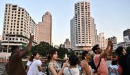 Tourists look at the view from the top deck of a tourist commuter boat on the Chao Praya River in Bangkok on December 27, 2023. (Photo by Lillian SUWANRUMPHA / AFP)
