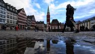 A pedestrian is reflected in a puddle as he walks at the Roemerplatz, the city's central square in Frankfurt am Main, western Germany, on January 3, 2024. Photo by Kirill KUDRYAVTSEV / AFP