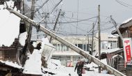 This photo taken on January 8, 2024 shows a woman walking under a downed utility pole after snow blanketed the disaster-hit area in the city of Suzu, Ishikawa prefecture, a week after a major 7.5 magnitude earthquake struck the Noto region in Ishikawa prefecture on New Year's Day. Photo by JIJI Press / AFP
