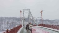 Local residents walk on a bridge over the Dnipro River in Kyiv, on January 14, 2024, amid the Russian invasion of Ukraine. (Photo by Roman PILIPEY / AFP)