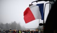 Farmers of the CR47 union (Coordination rurale 47), next to French flag on a tractor, attend a blocking of the A62 highway near Agen, southwestern France, on January 27, 2024.(Photo by Christophe ARCHAMBAULT / AFP)
