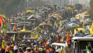 Farmers gather along a highway blocked by police to prevent them from marching towards New De;hi during a protest demanding minimum crop prices, near the Haryana-Punjab state border at Shambhu in Patiala district on February 16, 2024. (Photo by Narinder NANU / AFP)
