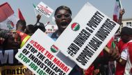 A protestor holds placards during a protest in Abuja on February 27, 2024. (Photo by Kola Sulaimon / AFP)
