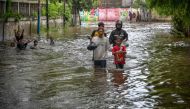 People walk through floodwaters due to heavy rainfall in a residential area in Jakarta on February 29, 2024. (Photo by BAY ISMOYO / AFP)