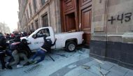 Demonstrators push a pickup truck to break down a presidential palace door in Mexico City on March 6, 2024, during a protest over the disappearance of the 43 students of the Ayotzinapa teaching training school in 2014. (Photo by Valentina Alpide / AFP)