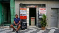 Shoemaker Amilcar Rodriguez, 52, sits outside his store in the central region of Sao Paulo, Brazil on March 20, 2024. (Photo by Miguel SCHINCARIOL / AFP)

