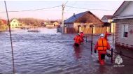 This photo taken from a video released by the Russian Emergency Situations Ministry on April 6, 2024 shows rescuers walking across a flooded street on their way to evacuate residents during a flood in the town of Orsk, Orenburg region, southeast of the southern tip of the Ural Mountains. (Photo by Handout / Russian Emergencies Ministry / AFP