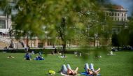 People enjoy the sunny and warm weather on a meadow at the public garden in Vienna on April 7, 2024. (Photo by GEORG HOCHMUTH / APA / AFP) / Austria OUT
