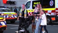 Families walk out of the Westfield Bondi Junction shopping mall after a stabbing incident in Sydney on April 13, 2024. (Photo by David Gray / AFP)