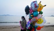 A balloon vendor walks on the beach in Qingdao, China's Shandong province on April 21, 2024. (Photo by WANG Zhao / AFP)
