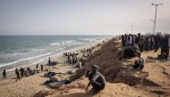 Palestinians watch fishermen returning at the beach next to a camp for the internally displaced in Rafah in the southern Gaza Strip on April 23, 2024. (Photo by AFP)

