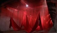 An installation of red ropes and empty dresses floats in the tunnel of the former concentration camp of Ebensee in the Salzkammergut region, 250 km west of Vienna, Austria, on April 26, 2024, during the opening of Japanese artist Chiharu Shiota's exhibition. Photo by KERSTIN JOENSSON / AFP.