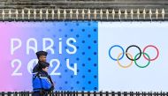 French Gendarmes walk past a banner for the forthcoming Paris 2024 Olympic Games outside The National Assembly - Assemblee nationale in Paris on May 5, 2024. (Photo by Stefano RELLANDINI / AFP)