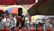 A fruit juice vendor displays a drink to customers during a hot summer day in the old quarters of New Delhi on May 17, 2024. (Photo by Arun Sankar / AFP)