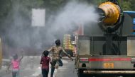 Children run behind a truck spraying water along a street on a hot summer day in New Delhi on May 28, 2024. (Photo by Arun Sankar / AFP)
 