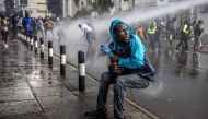 A protester reacts as a Kenyan police water canon sprays water at them during a demonstration against tax hikes in downtown Nairoibi, on June 20, 2024. (Photo by Luis Tato / AFP)