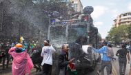 Protesters are perched on a police water cannon as it attempts to repel them with chemically treated water jets during a nationwide strike to protest against tax hikes and the Finance Bill 2024 in downtown Nairobi, on June 25, 2024. (Photo by Tony KARUMBA / AFP)
