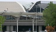 People walk past the collapsed terminal roof of New Delhi's Indira Gandhi International Airport after heavy rains in New Delhi on June 28, 2024. Photo by Arun SANKAR / AFP.